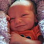 Tony is registered to the contest to win money with this photo: baby, smiling, close_up, blanket, purple, cozy, infant, face, hand, cute, soft_texture, child, wrapped, sleepy, warm, newborn, portrait, skin, happy, resting