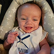 Tony joined the competition — help win amazing prizes! baby, smiling, infant, face, hand, clothing, sleeveless_shirt, baseball, text, cushion, star_pattern, seat, happy, tongue_out, person, indoor, cute, child, skin, head