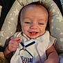 baby, smiling, infant, face, hand, clothing, sleeveless_shirt, baseball, text, cushion, star_pattern, seat, happy, tongue_out, person, indoor, cute, child, skin, head