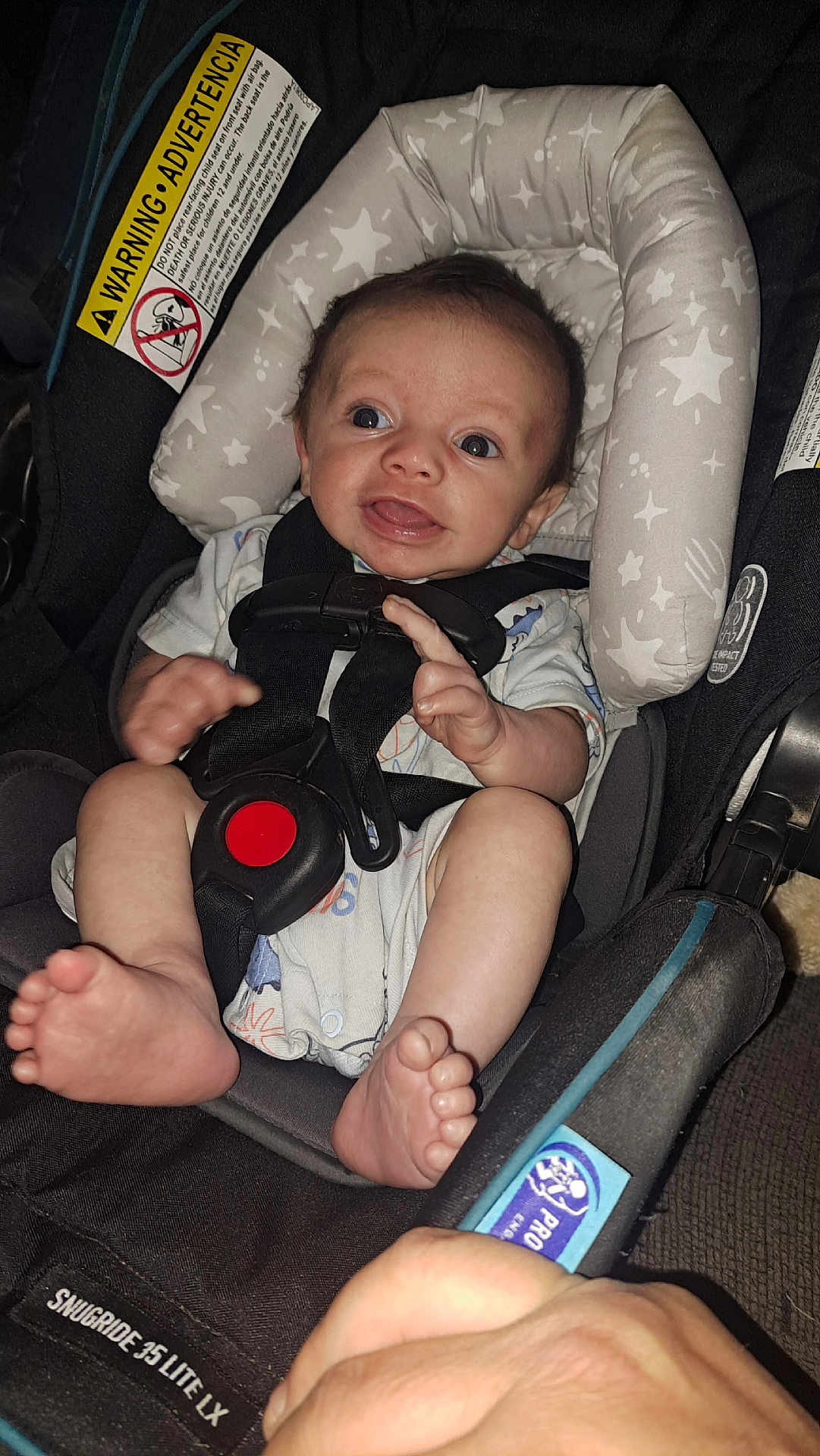 Tony joined the competition — help win amazing prizes! baby, car_seat, child, infant, seatbelt, safety, smile, hand, foot, clothing, fabric, padding, star_pattern, black, white, blue, person, face, indoors, closeup