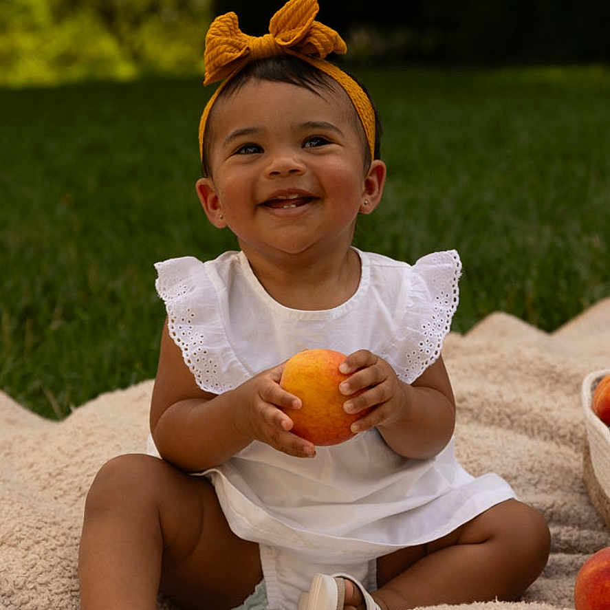 Phoenix is registered to the contest to win money with this photo: accessories, baby, bodypart, citrusfruit, face, finger, food, fruit, grapefruit, grass, hand, happy, head, person, photography, plant, portrait, produce, pumpkin, vegetable