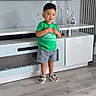 William joined the competition — help win amazing prizes! child, boy, toddler, smiling, standing, portrait, indoors, living_room, television, tv_cabinet, furniture, green_shirt, shorts, sandals, wood_floor, home, decor, wall, happy, full_body