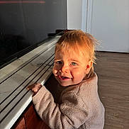 June a rejoint le concours — aidez-le/la à gagner de superbes lots ! baby, child, clothing, countertop, cozy, curly_hair, cute, face, happy, home, indoor, light, marble, natural_light, person, smiling, standing, sweater, toddler, wooden_floor