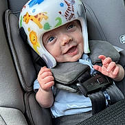 Felix is registered to the contest to win money with this photo: baby, helmet, car_seat, smile, blue_eyes, animal_print, infant, child, safety, seatbelt, cute, happy, clothing, hand, headgear, closeup, transportation, car_interior, protection, infancy