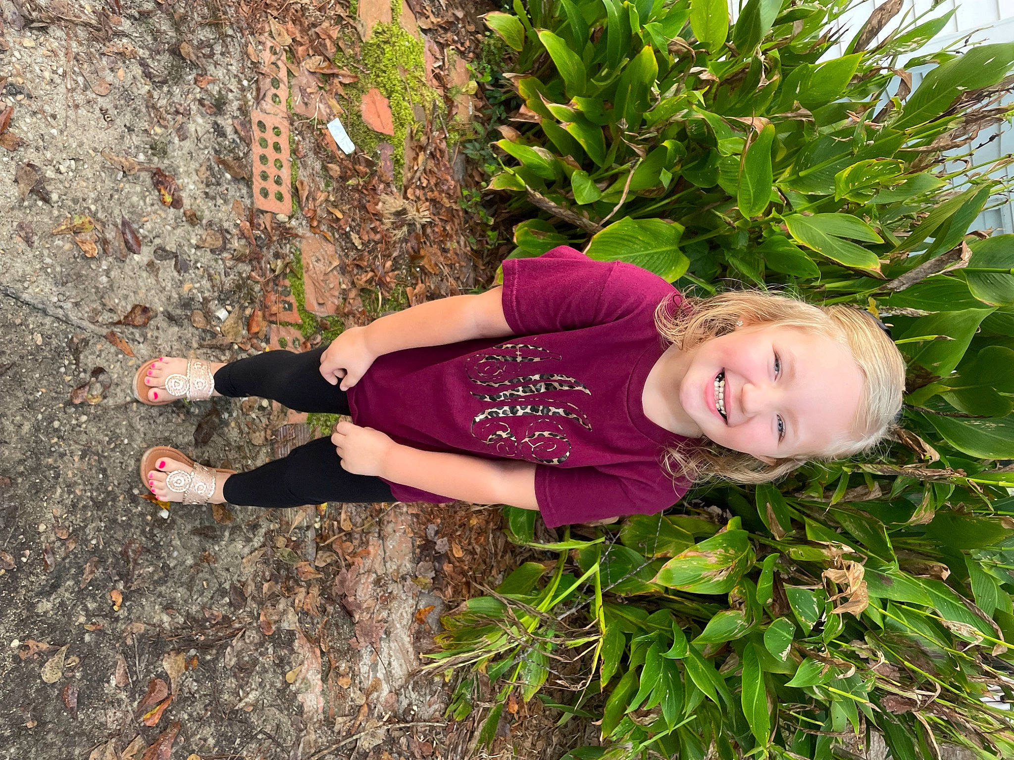 Anslee is registered to the contest to win money with this photo: child, flowering_plant, fun, garden, grass, grass_family, groundcover, happy, human_leg, joy, knee, magenta, people_in_nature, person, plant, shrub, smile, soil, t_shirt, terrestrial_plant