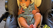 Solimar is registered to the contest to win money with this photo: baby, infant, stroller, pacifier, hat, cute, child, indoor, car_seat, footwear, keys, carpet, clothing, face, person, young_child, adorable, sitting, baby_girl, baby_boy