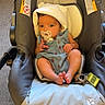 baby, infant, stroller, pacifier, hat, cute, child, indoor, car_seat, footwear, keys, carpet, clothing, face, person, young_child, adorable, sitting, baby_girl, baby_boy