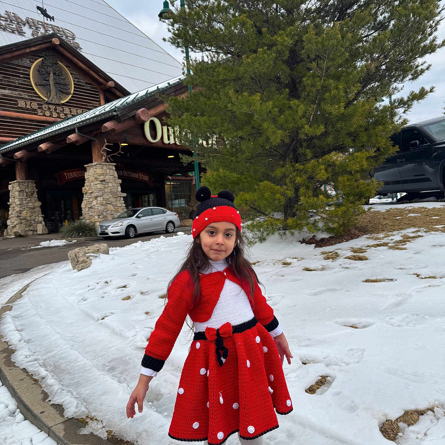 Noursan is registered to the contest to win money with this photo: building, car, child, curb, girl, holiday_outfit, knit_hat, log_cabin, outdoor_store, parked_car, pine_tree, polka_dot, portrait, red_dress, red_shoes, sidewalk, smile, snow, white_tights, winter