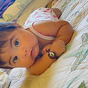 Leilani is registered to the contest to win money with this photo: baby, child, infant, bow, bracelet, quilt, starfish, bed, face, eyes, hair, pink, clothing, lying_down, portrait, cute, skin, hand, indoor, person