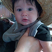 Enzo joined the competition — help win amazing prizes! baby, child, hat, straw_hat, face, hand, indoor, kitchen, curious, person, clothing, holding, adult_hand, black_hair, wide_eyes, expression, infant, portrait, cute, young