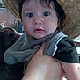 baby, child, hat, straw_hat, face, hand, indoor, kitchen, curious, person, clothing, holding, adult_hand, black_hair, wide_eyes, expression, infant, portrait, cute, young