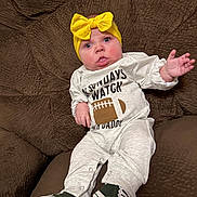 Laynee joined the competition — help win amazing prizes! baby, infant, child, portrait, sitting, couch, brown_couch, yellow_bow, headband, white_outfit, football_outfit, sneakers, raised_hand, waving, wide_eyes, smiling, indoor, close_up, fashion, photography