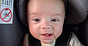 Montie joined the competition — help win amazing prizes! awake, baby, blanket, brown_hair, car_seat, casual_clothing, child, close_up, colorful_toys, face, green_blanket, indoor, infant, photography, portrait, safety_harness, seated, smiling, toy, vehicle