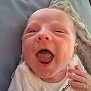 Montie is registered to the contest to win money with this photo: baby, infant, smiling, close_up, blanket, cozy, mouth_open, happy, cute, newborn, face, hand, skin, apparel, lying_down, indoors, expression, child, person, head