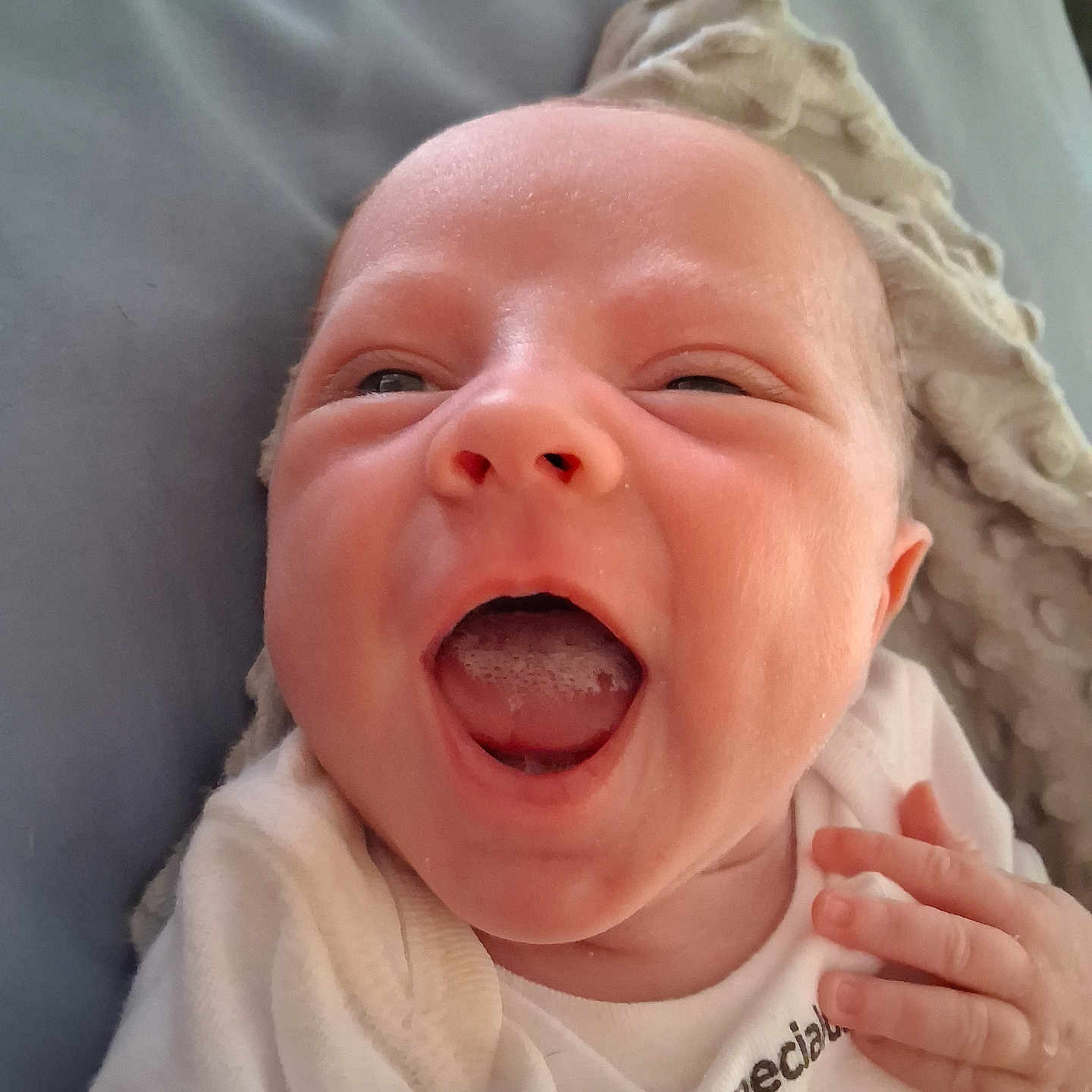 Montie is registered to the contest to win money with this photo: baby, infant, smiling, close_up, blanket, cozy, mouth_open, happy, cute, newborn, face, hand, skin, apparel, lying_down, indoors, expression, child, person, head