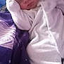 baby, newborn, sleeping, white_clothing, hat, pom_poms, blanket, purple, cozy, infant, cute, soft, peaceful, resting, child, person, bedtime, warm, snuggled, portrait