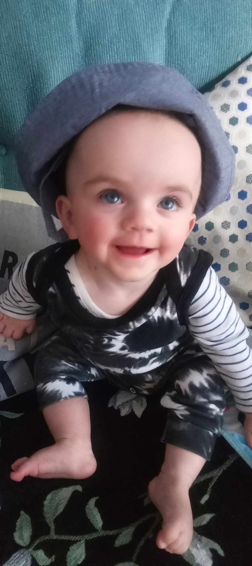 Mason is registered to the contest to win money with this photo: baby, child, smiling, hat, blue_eyes, striped_clothing, black_and_white_outfit, couch, cushion, indoor, happy, person, foot, hand, seated, portrait, infant, cute, home, patterned