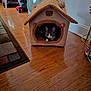 cat, cat_house, indoor, wooden_floor, fan, rug, pet, cozy, gray_cat, white_cat, animal, home, furniture, flooring, household_items, resting, cute, soft_toy, teddy_bear, pet_accessory