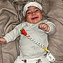 baby, smiling, infant, blanket, white_clothing, mickey_mouse, pacifier, pacifier_clip, headwear, cute, lying_down, happy, child, soft_texture, indoor, person, small_hands, buttoned_sweater, playful, cozy