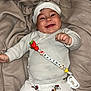 baby, smiling, infant, white_clothing, mickey_mouse, pacifier, blanket, hat, cute, lying_down, child, happy, soft_texture, indoor, one_person, close_up, person, clothing, accessory, infant_toys