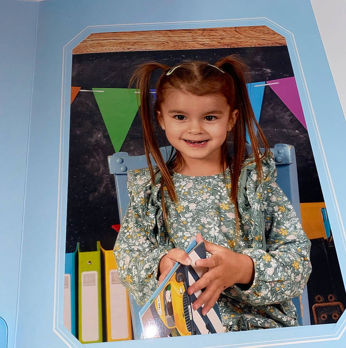 Eléonore a rejoint le concours — aidez-le/la à gagner de superbes lots ! book, chair, child, classroom, clothing, colorful, decor, flags, folders, girl, hair, happy, indoors, person, pigtails, portrait, reading, sitting, smile, young