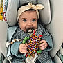 Emie a rejoint le concours — aidez-le/la à gagner de superbes lots ! baby, child, car_seat, headband, toy, pacifier, clothing, jacket, hand, face, eyes, seatbelt, indoor, comfort, cute, infant, fabric, colorful, sitting, smile