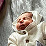 newborn, baby, sleeping, white_hoodie, knitted_clothing, blanket, soft_texture, peaceful, closeup, infant, portrait, cute, warm, resting, child, face, buttoned_jacket, indoors, cozy, sleep