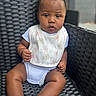 baby, bib, child, closeup, curious, cute, expression, furniture, infant, outdoor, person, pink_bow, portrait, sitting, skin, sock, soft_lighting, white_onesie, woven_chair, young
