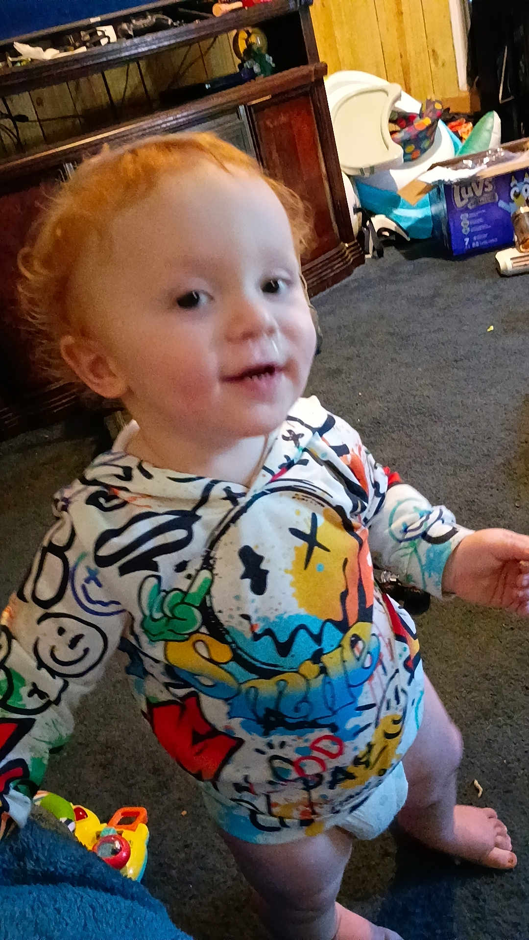 Paul Knight joined the competition — help win amazing prizes! toddler, child, hoodie, colorful_clothing, barefoot, carpet, toy, indoor, furniture, cabinet, diaper, red_hair, face, smiling, person, playful, room, household_items, candid, young_child