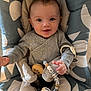 baby, infant, smiling, face, child, baby_seat, pacifier, toy, beads, cushion, clothing, grey, pattern, happy, cute, portrait, indoor, person, comfort, young_child
