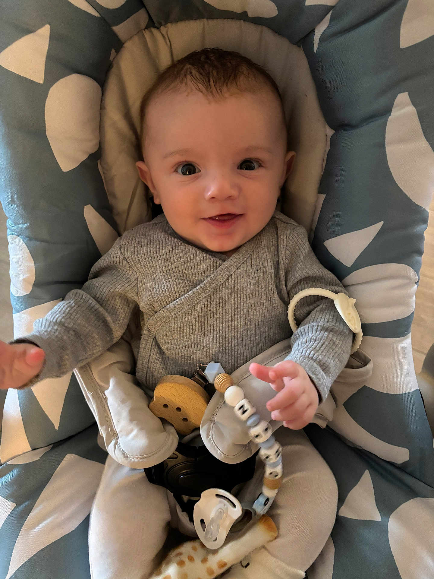 Nino a rejoint le concours — aidez-le/la à gagner de superbes lots ! baby, infant, smiling, face, child, baby_seat, pacifier, toy, beads, cushion, clothing, grey, pattern, happy, cute, portrait, indoor, person, comfort, young_child