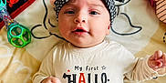 Lainey joined the competition — help win amazing prizes! baby, infant, headband, bow, shirt, text, halloween, toy, blanket, lying_down, cute, face, clothing, child, indoors, smiling, person, expression, playful, colorful