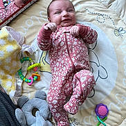 Lainey is registered to the contest to win money with this photo: baby, infant, play_mat, onesie, floral_pattern, mirror, reflection, toys, rattle, plush_elephant, soft_blanket, carpet, smiling, lying_down, indoor, child, cute, colorful, happy, cozy