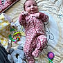 baby, infant, play_mat, onesie, floral_pattern, mirror, reflection, toys, rattle, plush_elephant, soft_blanket, carpet, smiling, lying_down, indoor, child, cute, colorful, happy, cozy