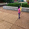 brick_wall, bubble_sword, bubbles, casual_clothing, child, concrete, daytime, fun, girl, greenery, leggings, outdoor, pink_shirt, play, side_view, sidewalk, sneakers, toy, urban, young
