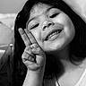 child, girl, peace_sign, smile, teeth, face, hand, black_and_white, portrait, closeup, happy, dimples, long_hair, casual_clothing, indoors, cute, expression, youth, person, skin