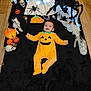 Ava a rejoint le concours — aidez-le/la à gagner de superbes lots ! baby, infant, child, pumpkin_costume, jack_o_lantern, halloween, smile, spider, ghost_decor, skull, blanket, wood_floor, costume, decorations, toy, candy, orange, black, portrait, holiday
