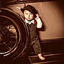 Camden is registered to the contest to win money with this photo: toddler, child, vintage_car, hat, pinstripe_suit, barefoot, wheel, oldtimer, sepia, portrait, curious, standing, retro, classic, vehicle, person, clothing, sidewalk, expression, nostalgic