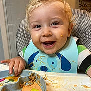 Camden is registered to the contest to win money with this photo: toddler, child, smiling, blonde_hair, high_chair, bib, spaghetti, messy, food, meal, indoor, happy, face, hand, plate, table, clothing, kitchen, person, cute