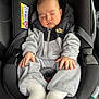 baby, sleeping, car_seat, hoodie, nike_logo, gray_clothing, white_socks, infant, child, seatbelt, car_interior, peaceful, hands, face, portrait, casual_wear, young_child, soft_lighting, cozy, resting