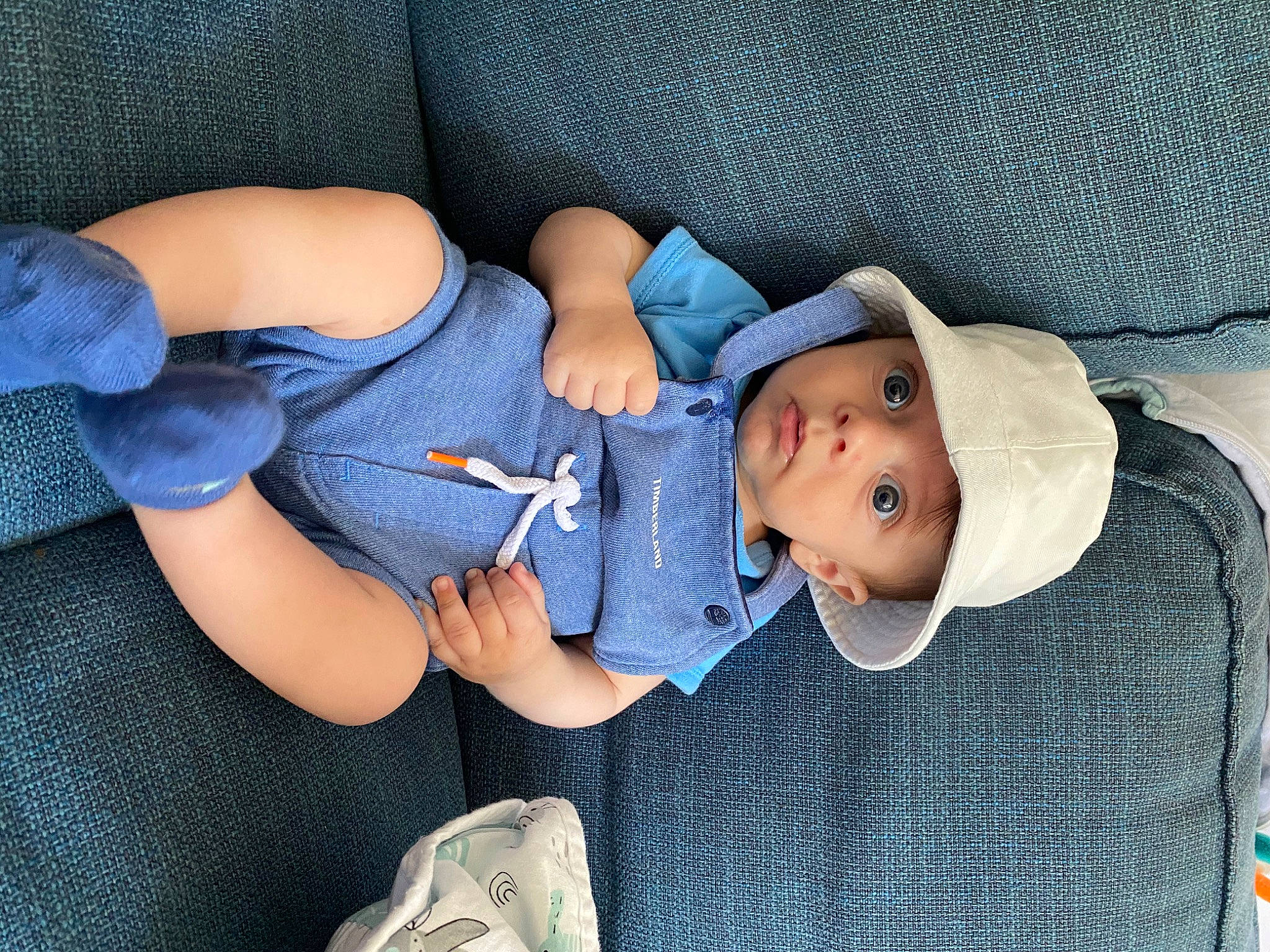 Augustin participe au concours pour gagner de l'argent avec cette photo : arm, baby, baby_carriage, baby_products, baby_toddler_clothing, blue, child, comfort, electric_blue, eye, face, finger, gesture, hand, hat, head, headwear, human_body, person, product