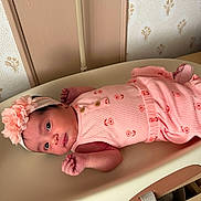 Ashley is registered to the contest to win money with this photo: newborn, baby, infant, child, portrait, lying_down, pink_outfit, floral_clothing, headband, flower, changing_table, nursery, nursery_decor, wallpaper, woven_basket, indoor, facial_expression, blue_eyes, hands, safe