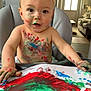 toddler, child, painting, paint, messy, high_chair, face_paint, indoor, living_room, art, colorful, baby, hands, paper, red_paint, green_paint, blue_paint, expression, smiling, creativity