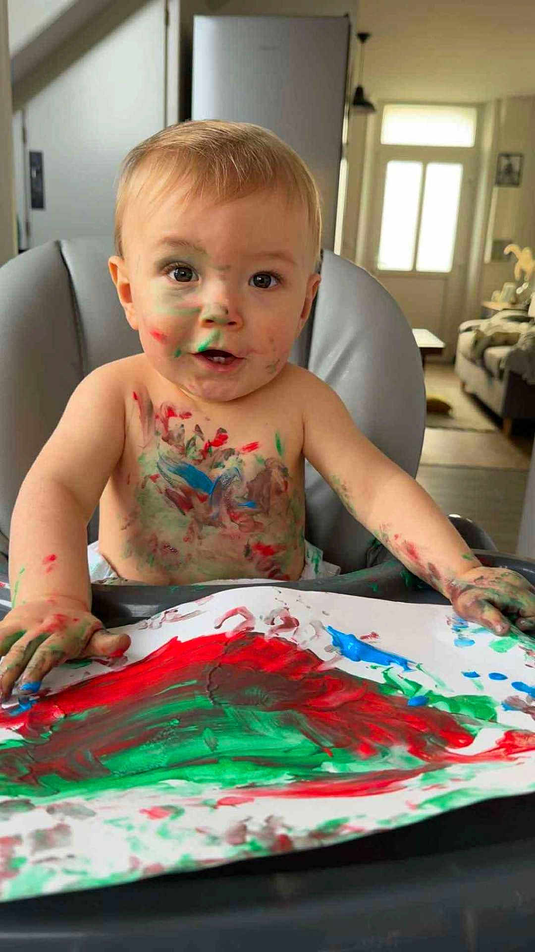 Aaron a rejoint le concours — aidez-le/la à gagner de superbes lots ! toddler, child, painting, paint, messy, high_chair, face_paint, indoor, living_room, art, colorful, baby, hands, paper, red_paint, green_paint, blue_paint, expression, smiling, creativity