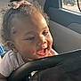 baby, child, car_seat, hair_bow, curly_hair, smiling, sunlight, car_interior, window, happy, infant, face, hand, clothing, seatbelt, toddler, portrait, cute, indoors, car