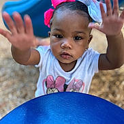Kehlani is registered to the contest to win money with this photo: child, close_up, colorful, curious, cute, daylight, expression, face, fun, hair_bow, hands, outdoor, person, play, playground, reaching, slide, toddler, white_shirt, young_child