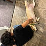 dog, person, floor, tile, carpet, indoor, petting, black_shirt, light_fur, collar, tail, paw, jeans, shoe, back, head, hair, relaxation, comfort, home