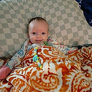 Carolyn is registered to the contest to win money with this photo: baby, beads, bed, bedding, blanket, blanket_pattern, checkered_pillow, cute, indoor, infant, lying_down, onesie, orange_pattern, pacifier_clip, pillow, portrait, smile, soft_fabric, toy, wide_eyes