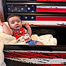american_flag, arms, baby, bib, blanket, blue, car, cartoon, child, clothing, cozy, drawer, face, furniture, indoor, infant, pattern, red, smiling, white