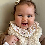 Léonie a rejoint le concours — aidez-le/la à gagner de superbes lots ! baby, smile, face, child, infant, clothing, vest, bow, portrait, cute, happy, hand, fabric, soft, warm, indoor, closeup, skin, person, young